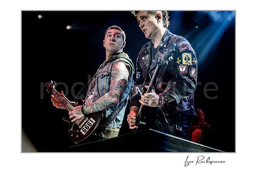 Horizontal color image of Zacky Vengeance and Synyster Gates of Avenged Sevenfold playing guitar together under cool stage lighting