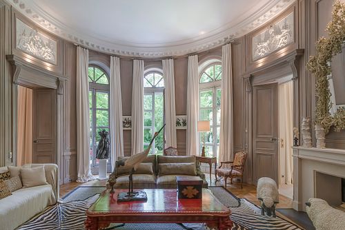 Salon circulaire haussmannien à Saint-Germain-des-Prés avec plafond moulu, grandes fenêtres donnant sur le jardin et mobilier élégant. Photographie d'architecture intérieure par Nicolas Karadimos