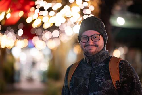Porträt eines Mannes im abendlichen Lichtermeer, unscharfe Lichtpunkte im Hintergrund