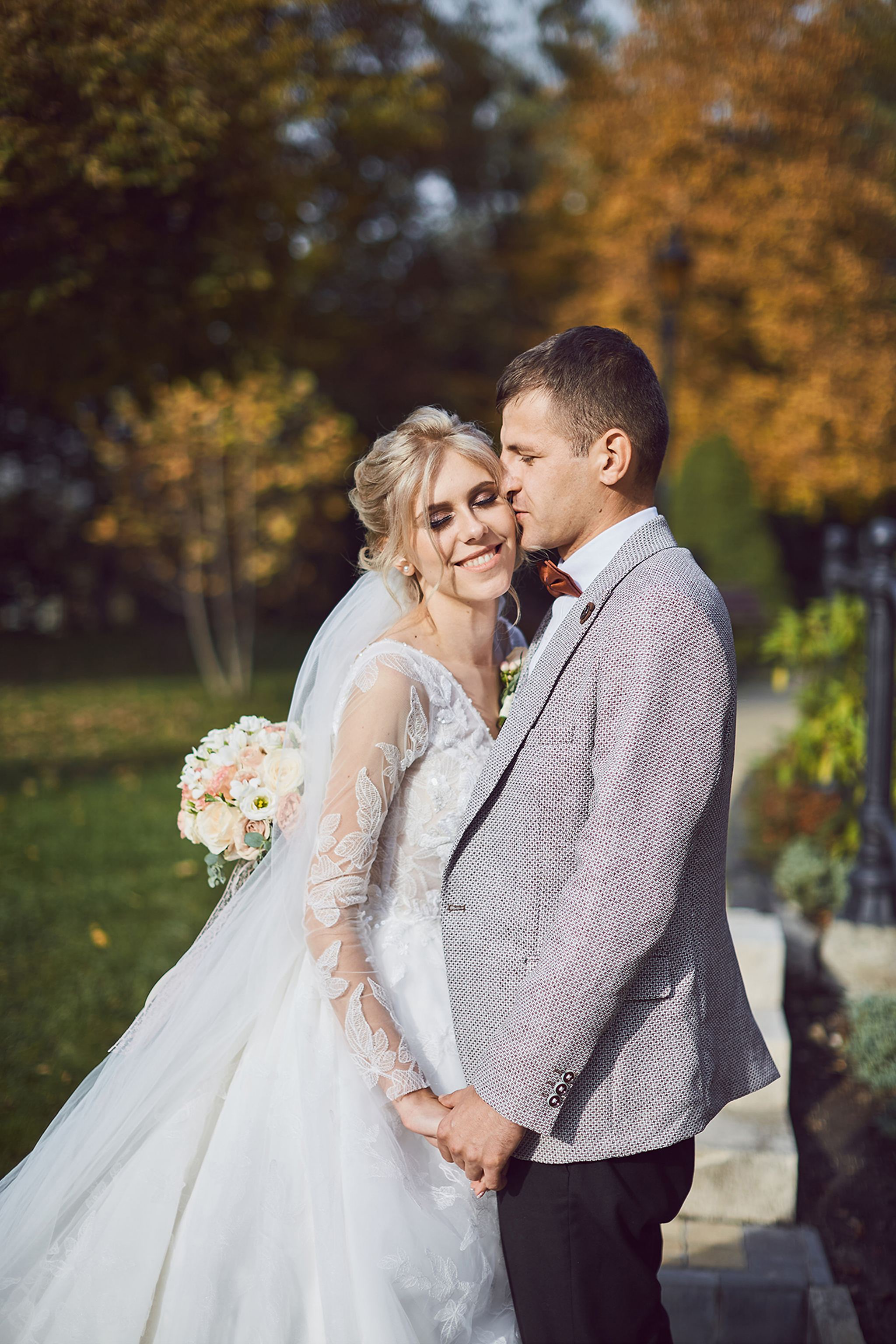 Groom kissing the bride during an autumn wedding portrait