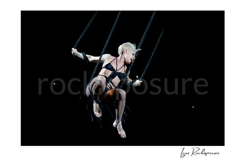 Horizontal color image of Pink suspended high above the stage on ropes during a dramatic live performance