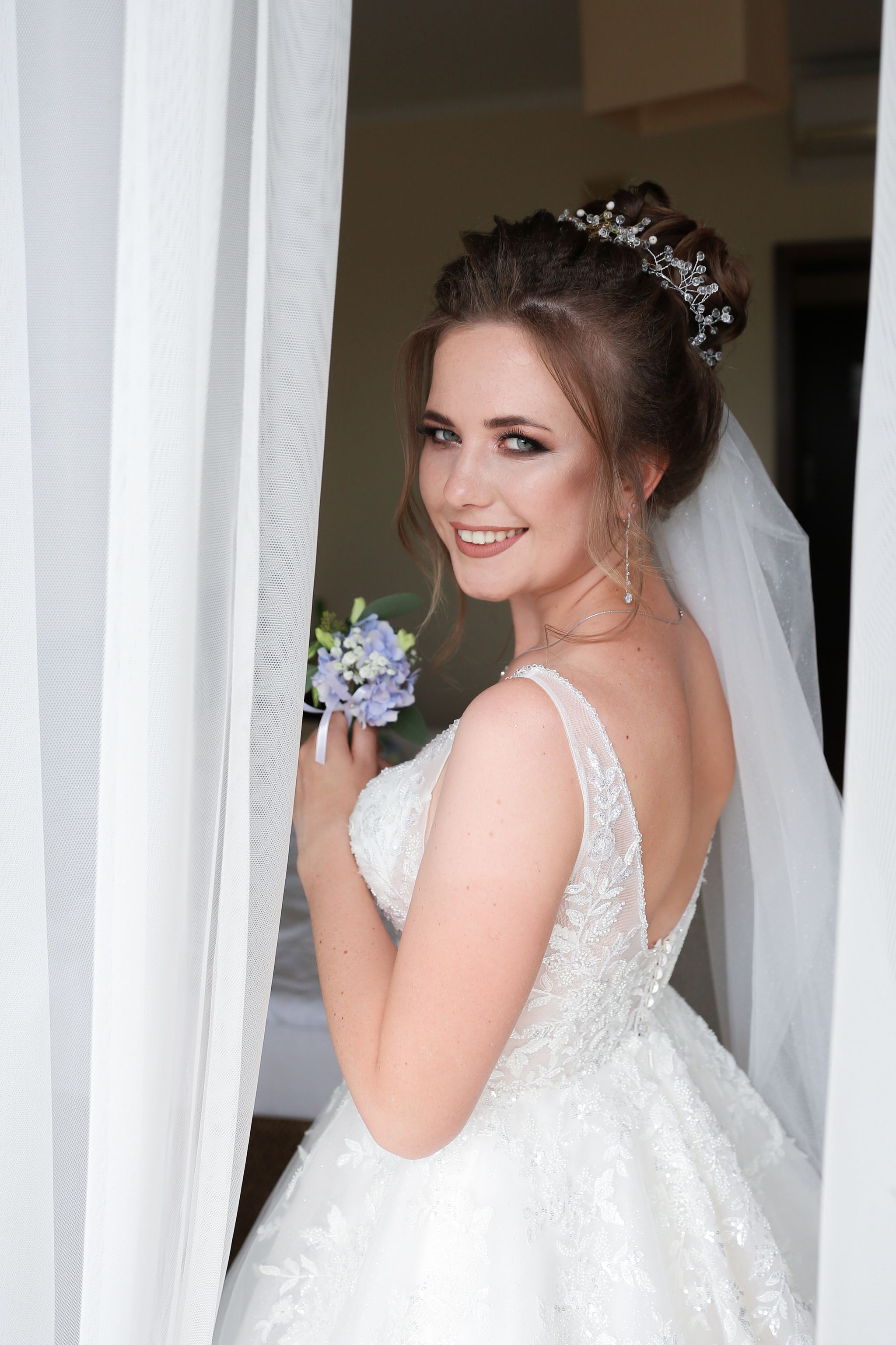 Bride looking out of the window during her wedding morning preparations