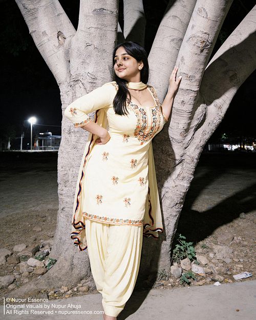 Shy fashion pose featuring Nupur Ahuja wearing a yellow embroidered salwar suit at night.
