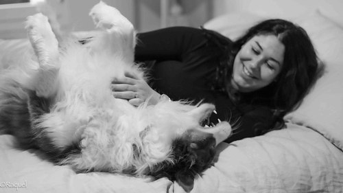 Femme enceinte allongée sur un lit partageant un moment de complicité avec son chien.