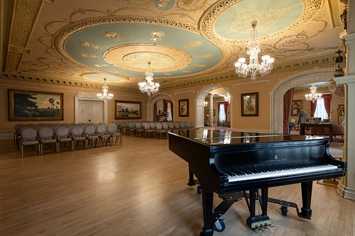 Intricate ceiling moldings with subtle gold accents above chandeliers and seating in the historic Grand Parlor.