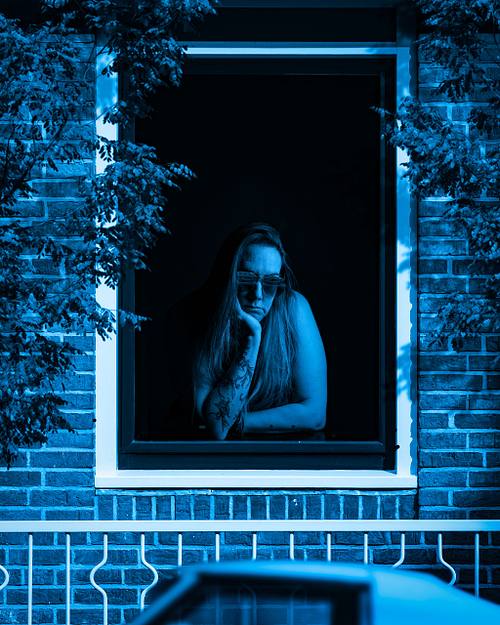 A blue scene of a woman wearing shades looking out the window a blue car.