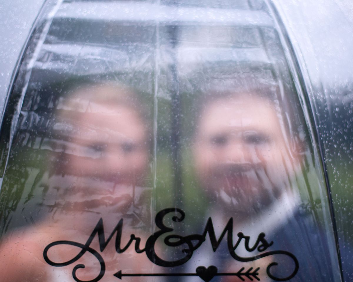 bride and groom under umbrella with their face blurred out