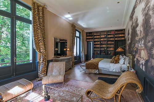 Chambre à coucher d’un appartement haussmannien de 400 m² rue du Faubourg Saint-Honoré avec papier peint panoramique, mobilier en rotin et grande fenêtre. Photographie d’architecture intérieure par Nicolas Karadimos.