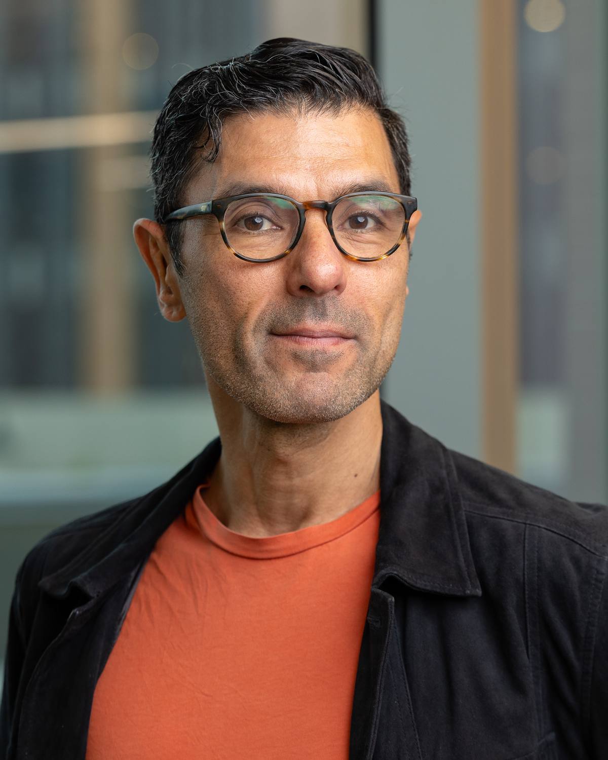 A man wearing glasses poses for a headshot at The Junction offices in Chapel Hill, NC