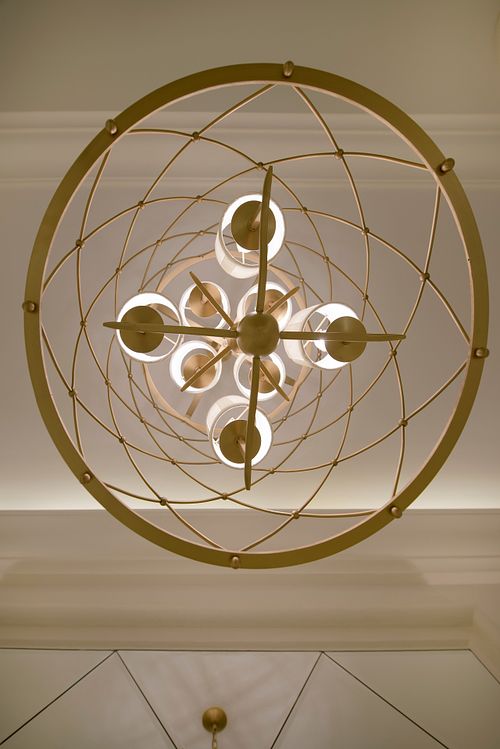 Suspension géométrique dorée vue du dessous avec structure en cercles concentriques, détail de luminaire dans un intérieur haussmannien