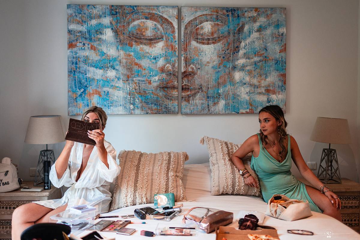 La mari&eacute;e se pr&eacute;pare devant un grand tableau abstrait, accompagn&eacute;e d'une amie dans une chambre cosy, sc&egrave;ne pr&eacute;-nuptiale photographi&eacute;e par S&eacute;bastien Clavel &agrave; N&icirc;mes