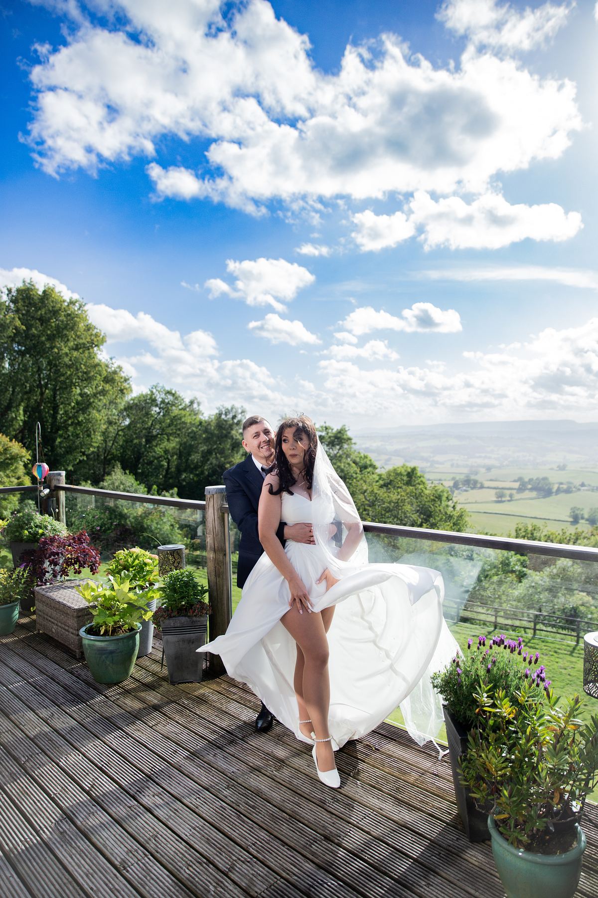 Bride and groom standing together on a terrace with a landscape view in South Wales