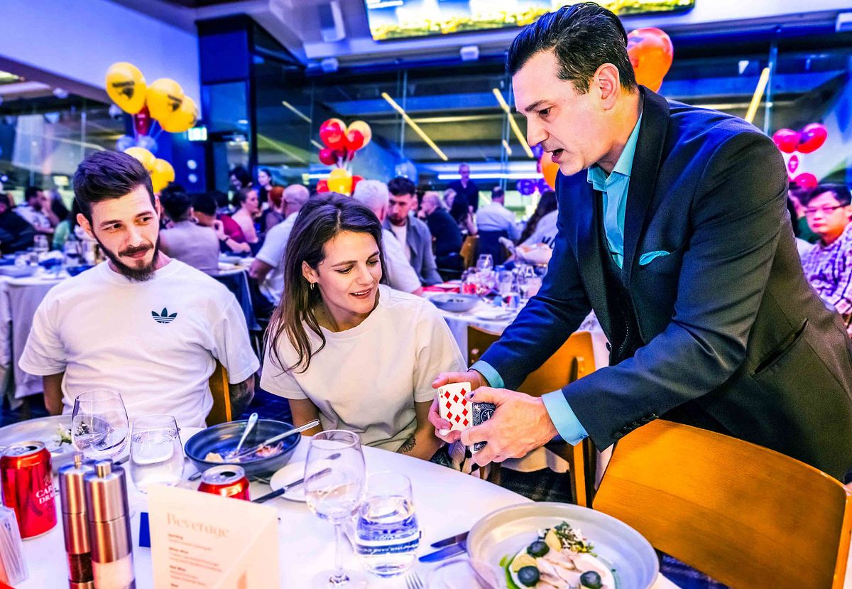 Magician and performer, Richard Vegas performs some magic tricks at tables during a corporate event.
