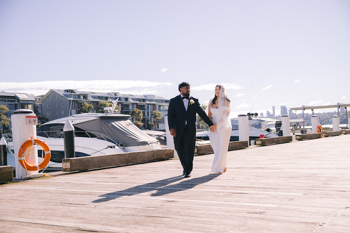 bride and groom holding hands walking at the waterfront next to Pyrmont Wedding Registry