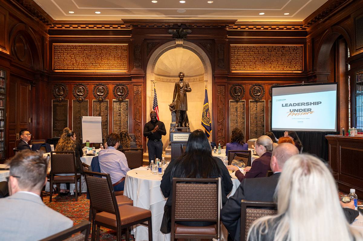 Presenter addresses attendees seated at round tables beneath an Abraham Lincoln statue at the Union League of Philadelphia.