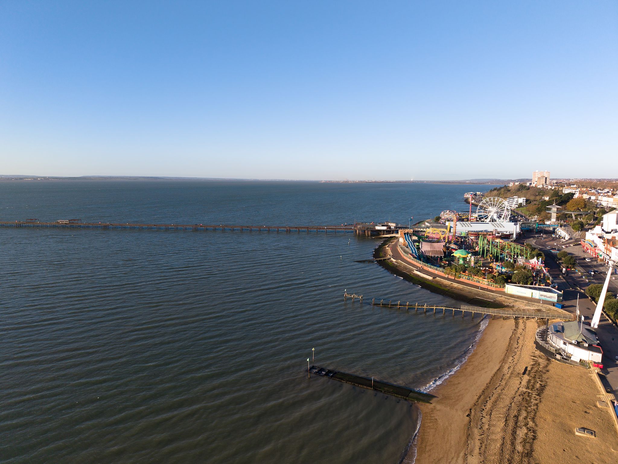Aerial photograph of Southend coastline, with sandy beach, and the pier extending into the sea during soft evening light