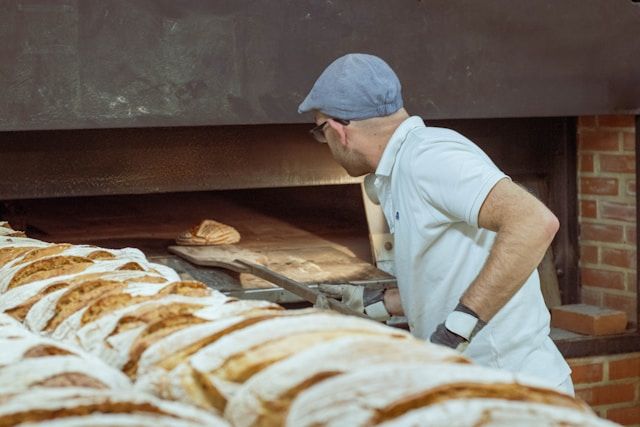 un fornaio che indossa una polo e un berretto in una panetteria