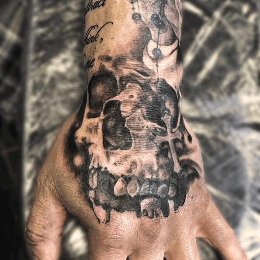 Black and grey hand tattoo featuring a detailed skull with rosary beads wrapped around the hand, high contrast realism shading created in Stoke-on-Trent by Alika Tattoo Art.