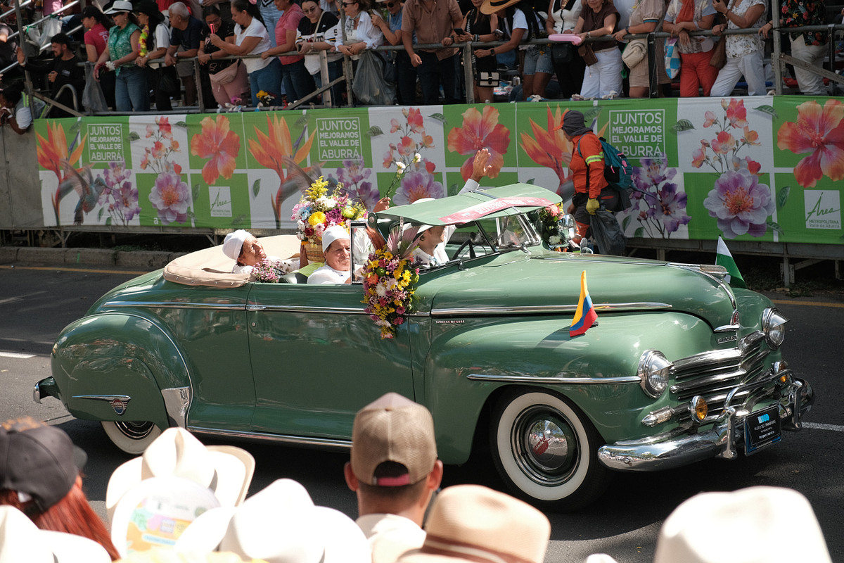 Auto clásico verde adornado con flores en el Desfile de Autos Clásicos y Antiguos de Medellín
