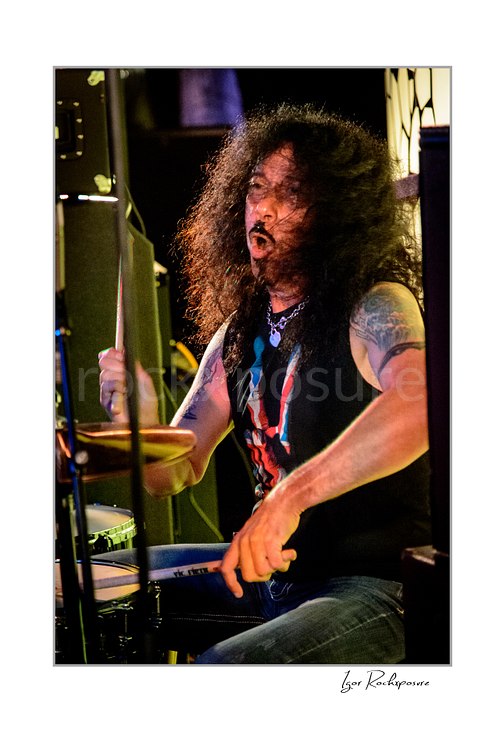 Vertical color image of Frankie Banali playing drums onstage with flying hair in a tight live performance shot