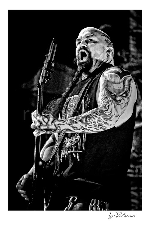 Vertical black and white image of Kerry King of Slayer playing guitar onstage in a tight live performance portrait