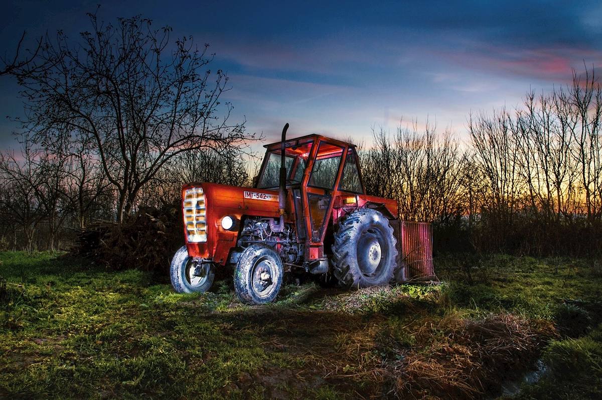 Roter Vintage-Traktor IMT 542 bei Dämmerung in Bosnien, kunstvoll inszeniert durch Lichtmalerei und Langzeitbelichtung aus 16 Einzelaufnahmen