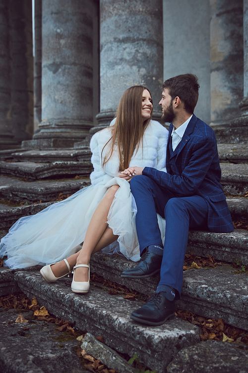Bride and groom sitting on the stone steps in Pidhirtsi