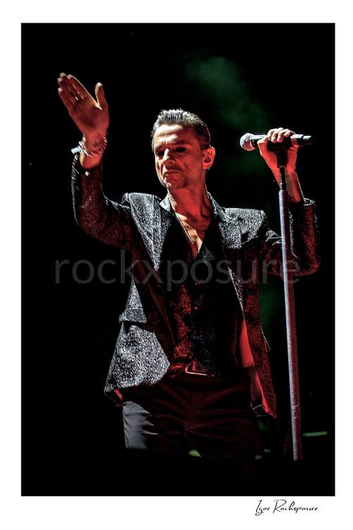 Vertical color image of Depeche Mode singer Dave Gahan performing beside a microphone stand during a live performance