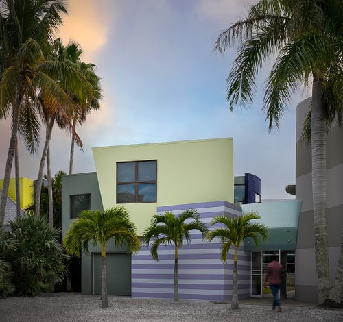 An aerial sunset photograph of the modern "Striped House" in Lido Shores, Sarasota, featuring bold geometric lines, a luxury pool, and distinct vertical shadow patterns.