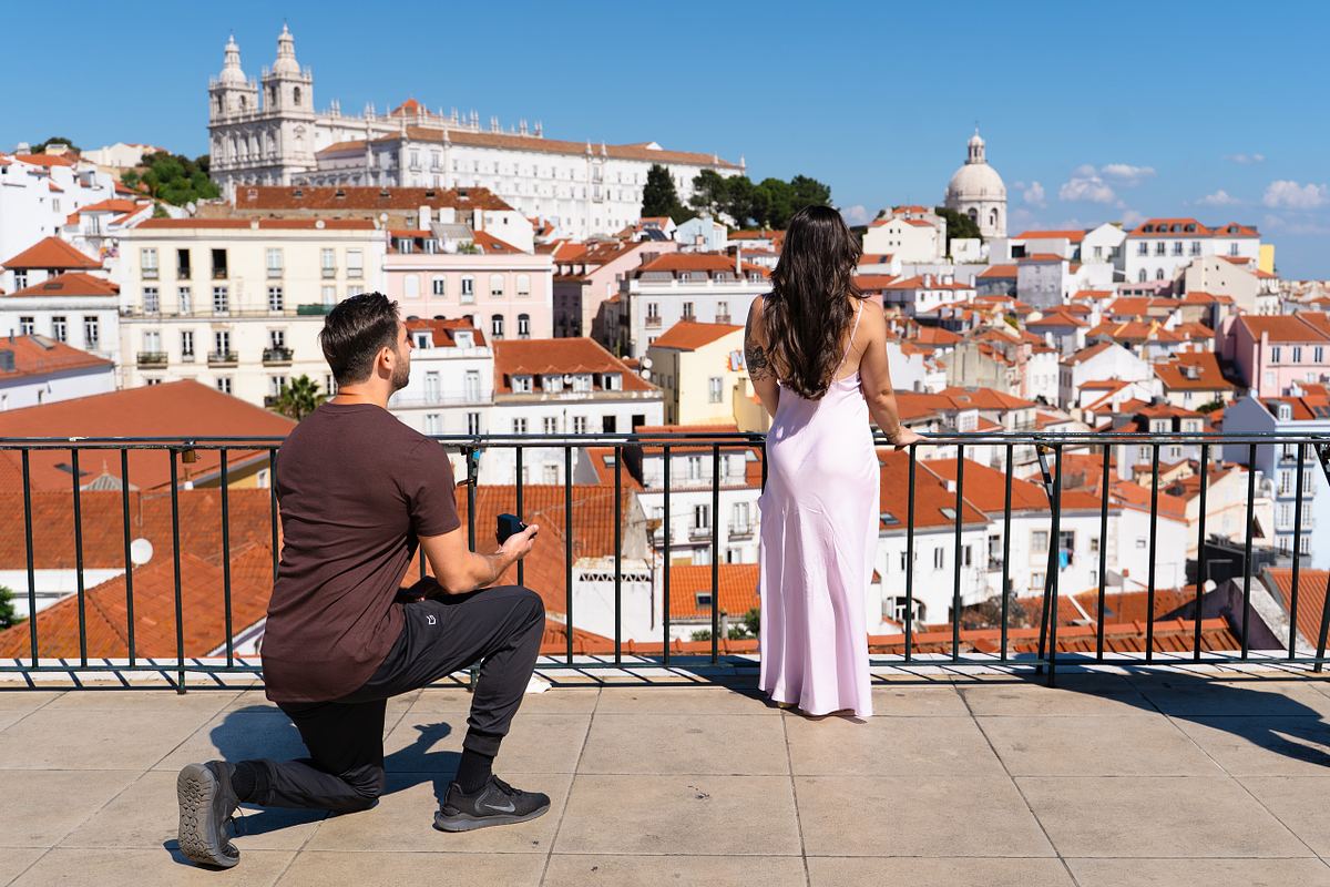 Man kneeling during a surprise marriage proposal overlooking Lisbon
