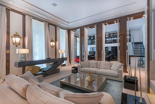 Salon contemporain à Saint-Germain-des-Prés avec canapés beiges, grande table basse miroir et vue sur l'escalier. Photographie d'architecture intérieure par Nicolas Karadimos.