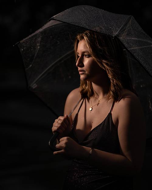 Edmonton High School Grad standing under an umbrella in the rain.