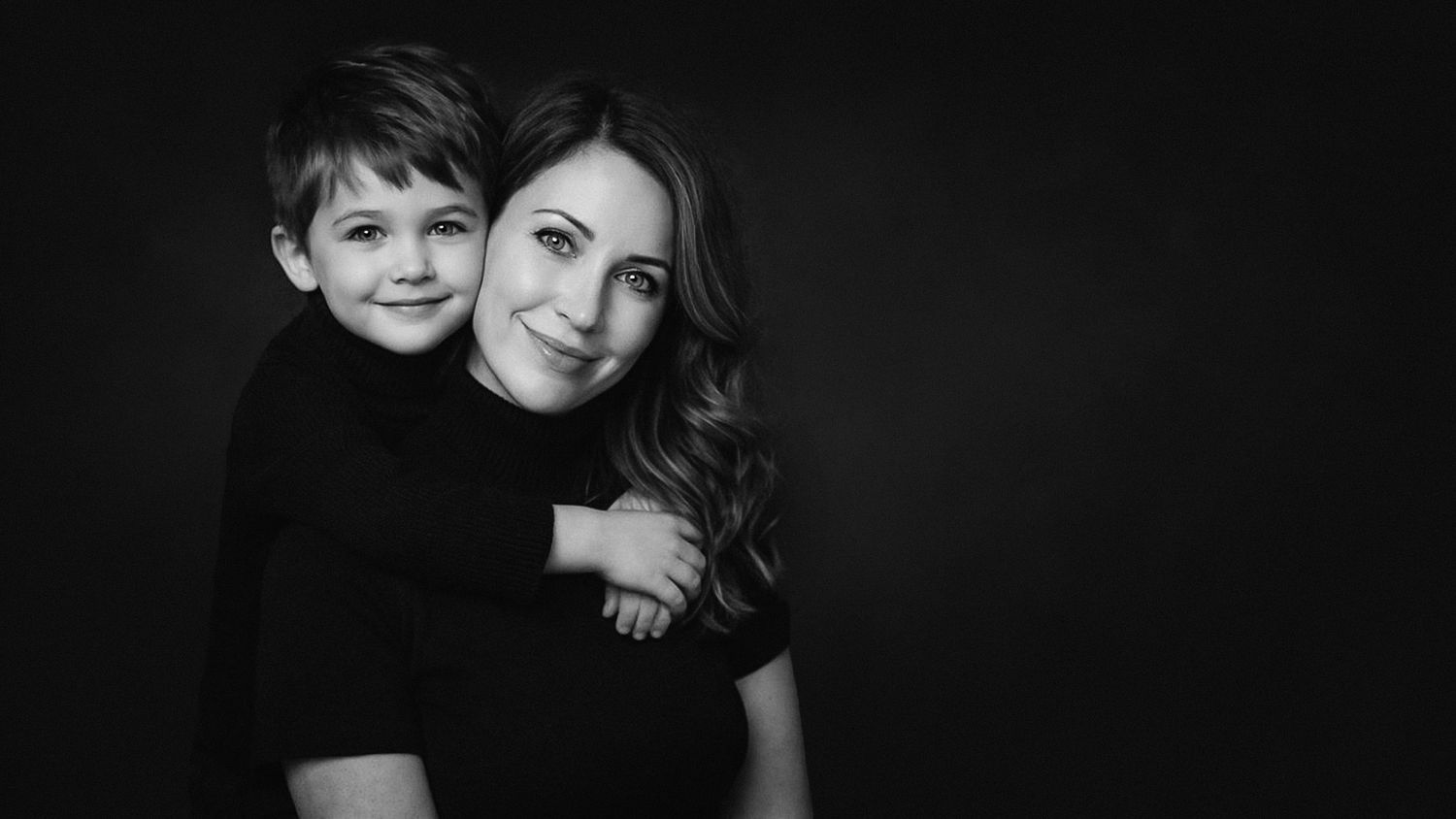 Black and white studio portrait of a mother and little son embracing in Tallinn