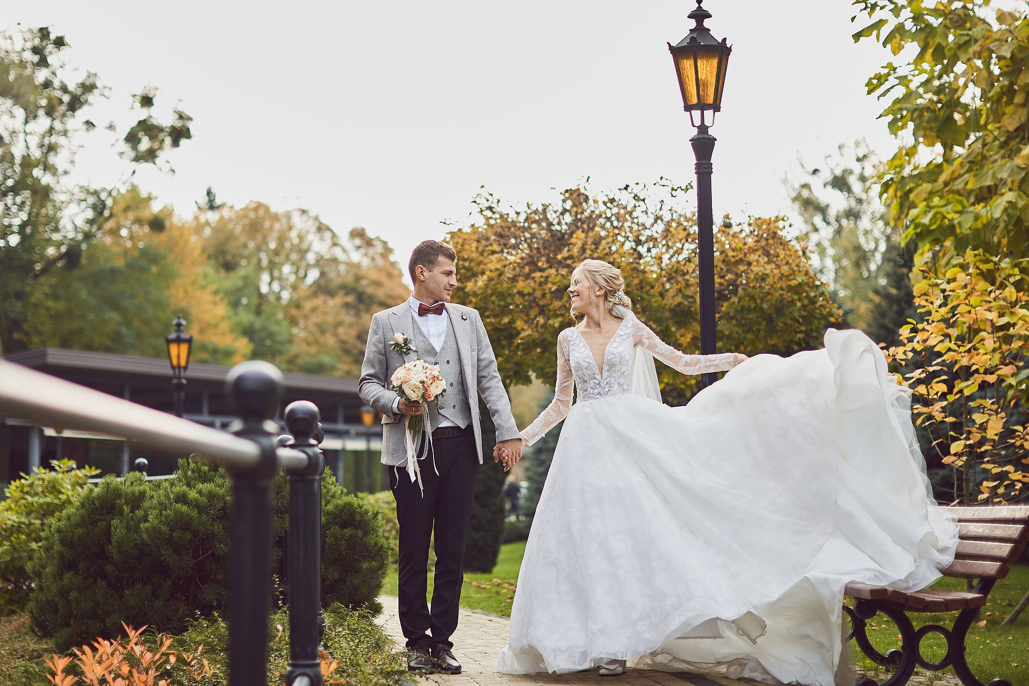Bride and groom walking hand in hand through an autumn garden