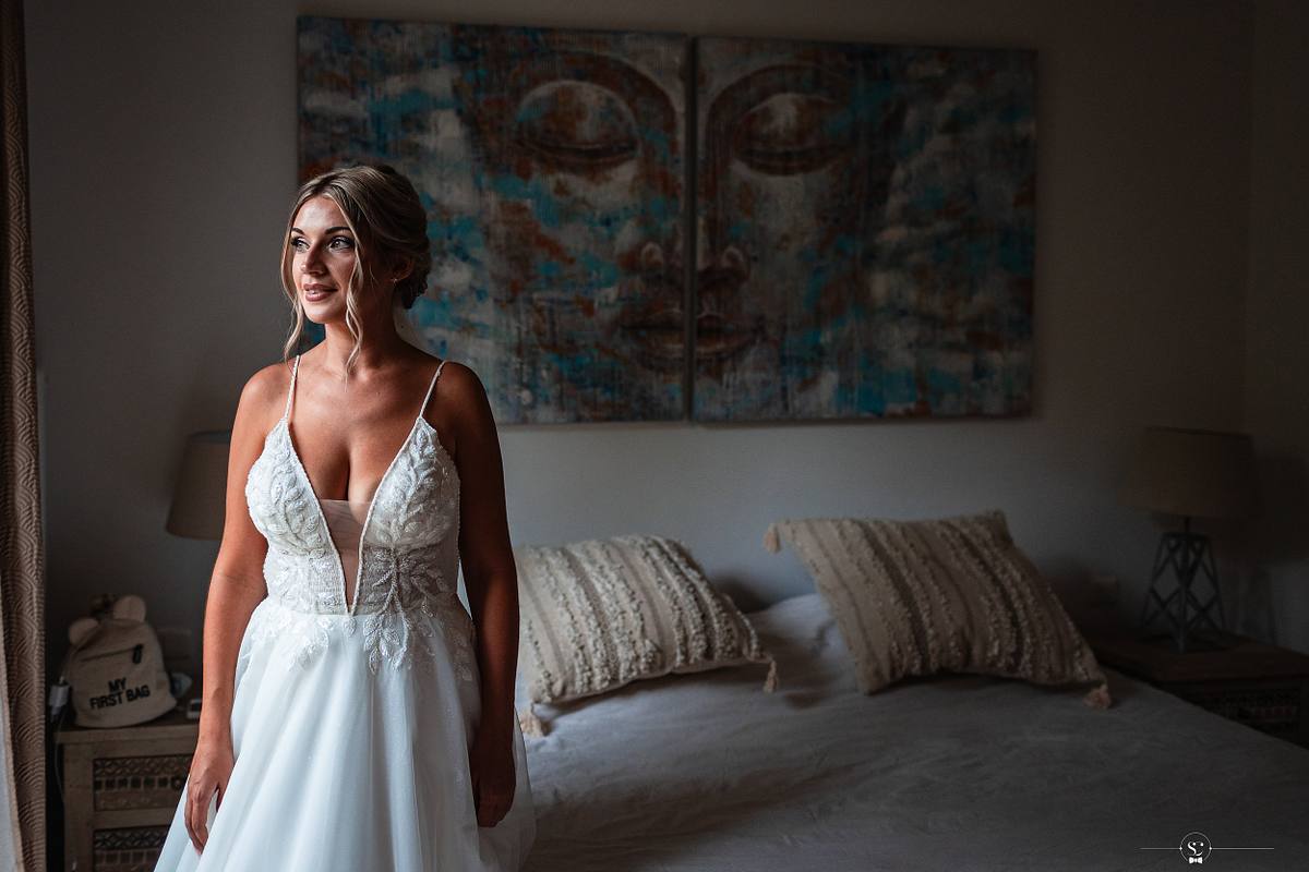 Portrait de la mari&eacute;e au regard captivant, debout dans une chambre d&eacute;cor&eacute;e d'art moderne, incarnant la beaut&eacute; et l'anticipation juste avant de se joindre &agrave; la c&eacute;r&eacute;monie de mariage simple mais significative &agrave; N&icirc;mes