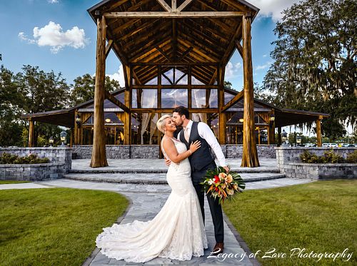 Bride and groom embracing beneath the pavilion at The Barn at Cottonwood Ranch near Jacksonville