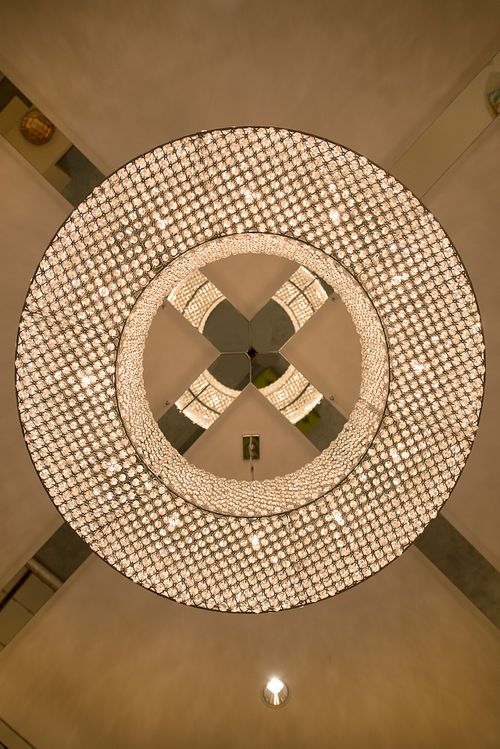 Vue plongeante sur un lustre circulaire monumental composé de milliers de cristaux, détail du plafond dans un intérieur haussmannien