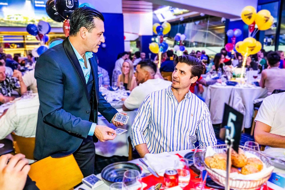 Magician and performer, Richard Vegas performs some magic tricks at tables during a corporate event.