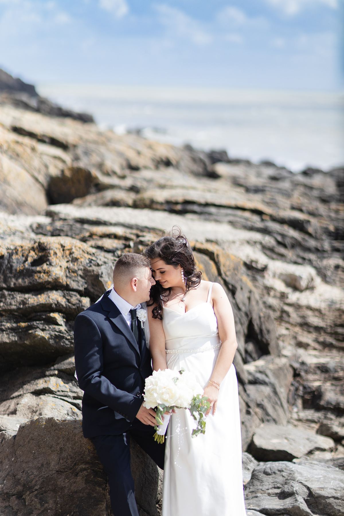 Bride and groom sharing a quiet moment among the rocks at Barry Island, South Wales