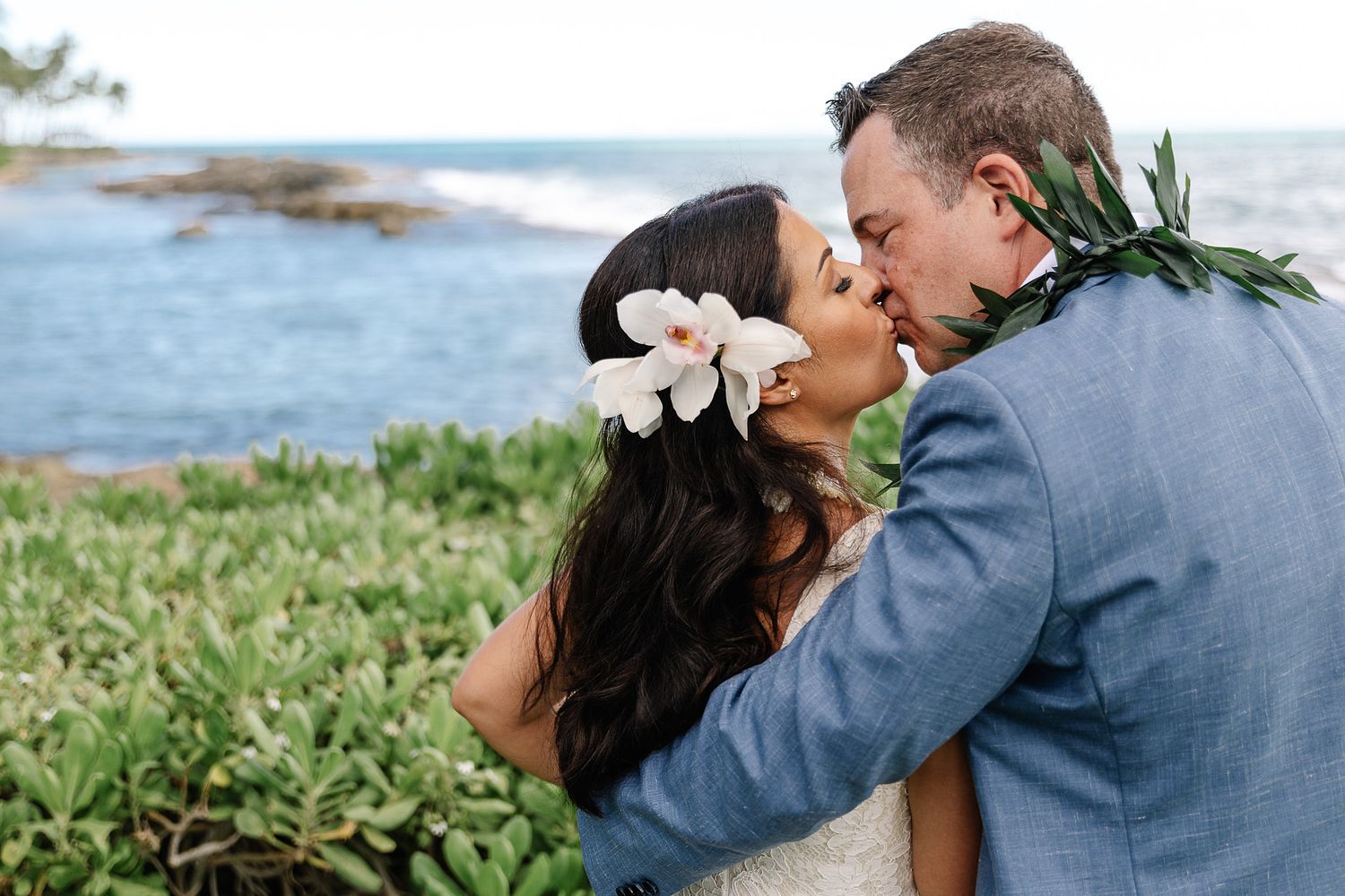 Newlywed couple kissing by the ocean during their destination wedding in Oahu, Hawaii