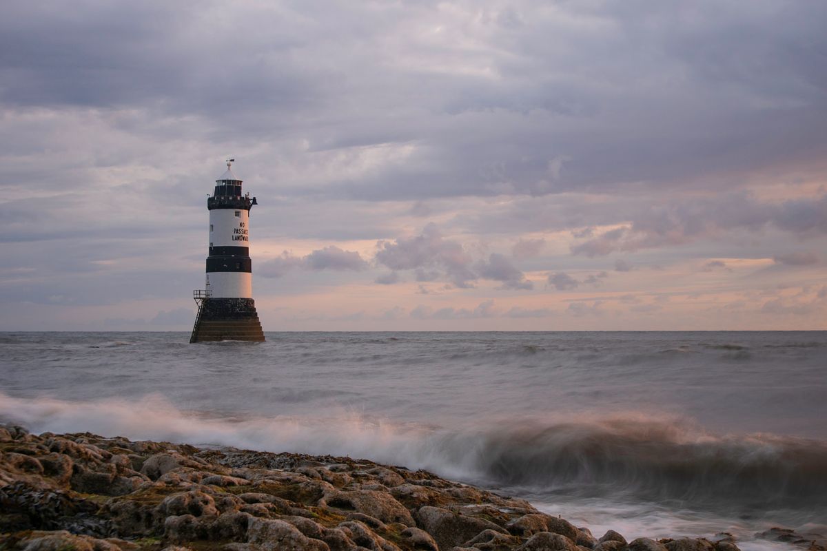 Penmon Point lighthouse on the Welsh coast beneath cloudy skies