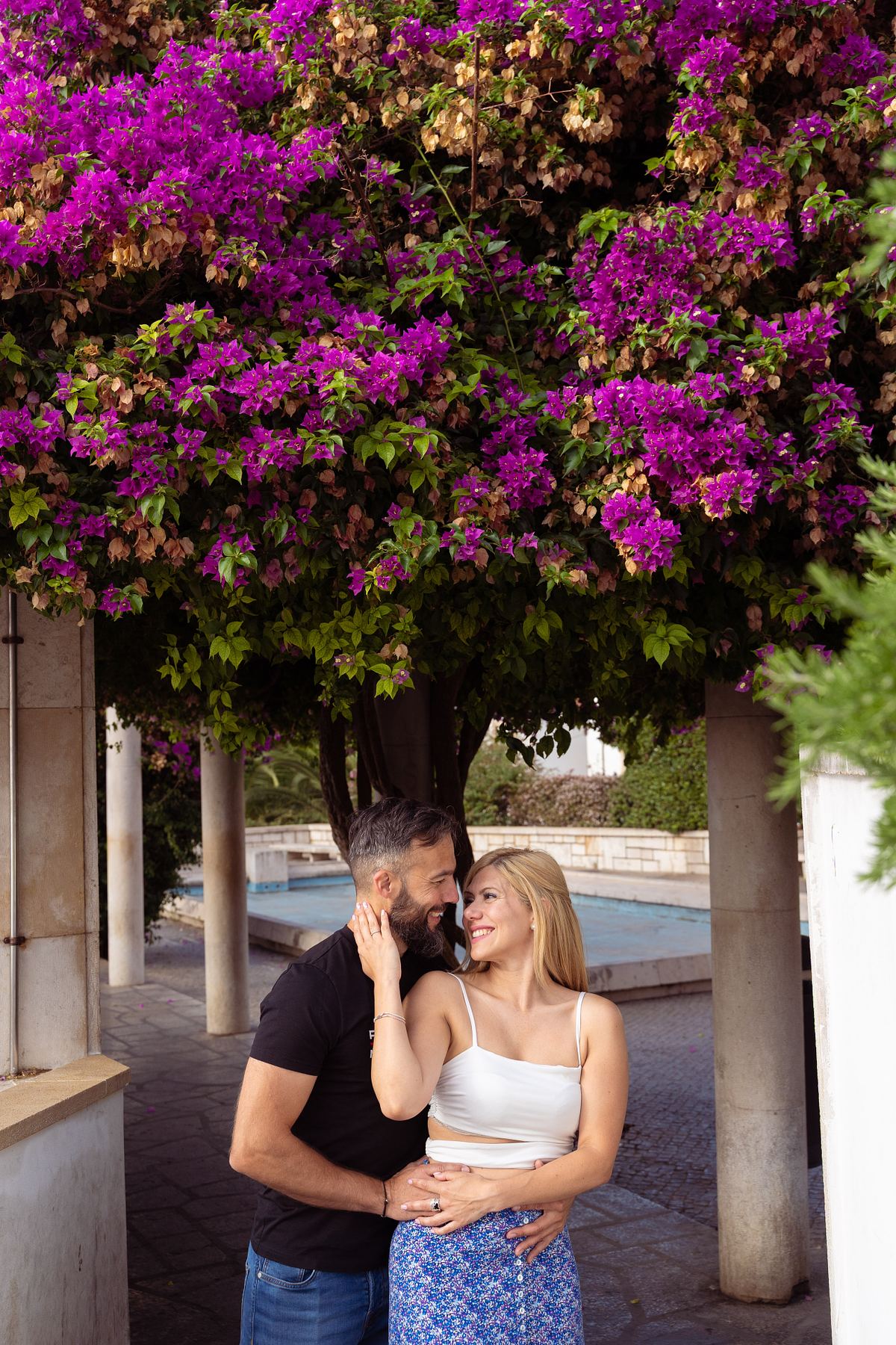Couple sitting beneath purple bougainvillea in Lisbon