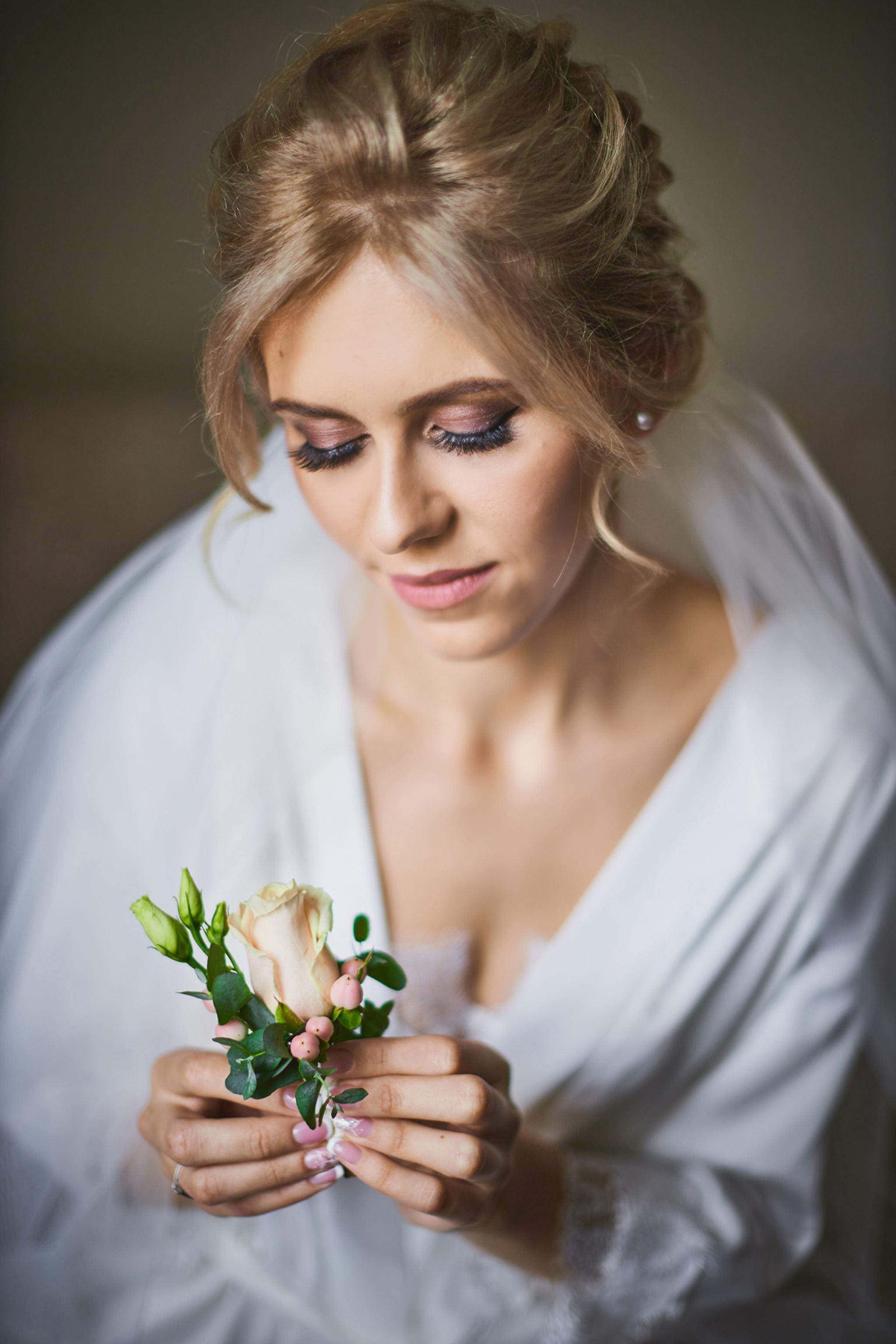 Bride holding a delicate floral detail during wedding preparations
