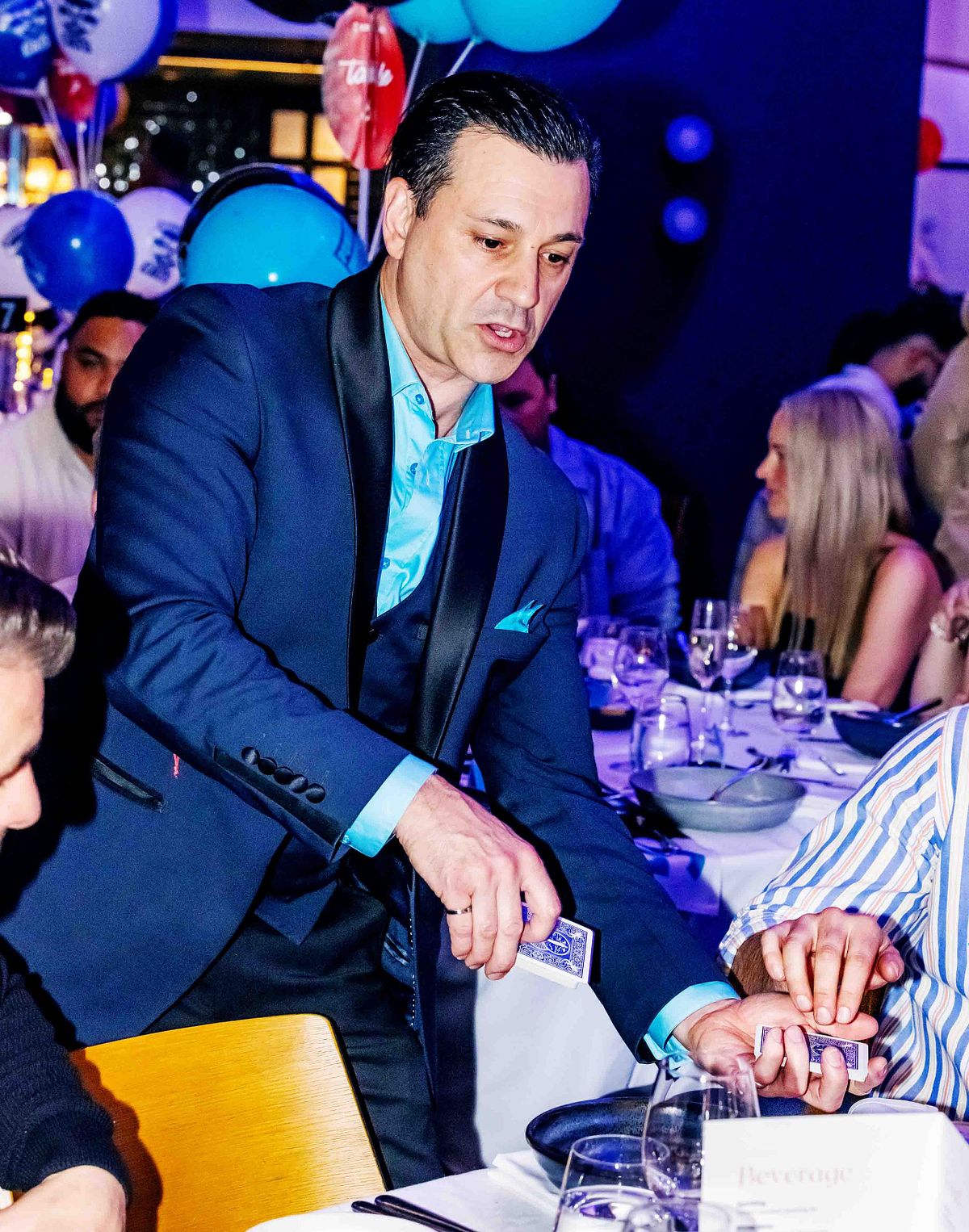 Magician and performer, Richard Vegas performs some magic tricks at tables during a corporate event.