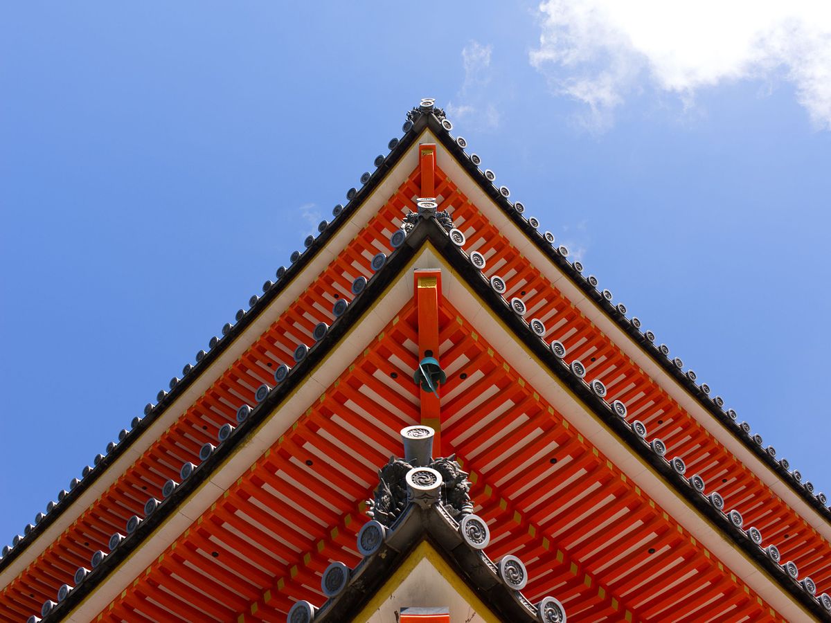 Dettagli raffinati di un tempio a Kyoto, con tetti e decorazioni tradizionali stagliati contro un cielo sereno, testimone di storia e calma