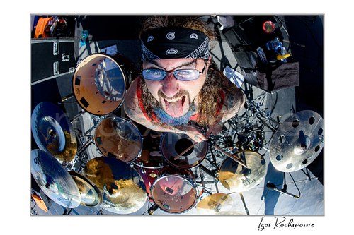 Mike Portnoy Live Concert Print  Horizontal color image of Mike Portnoy in an exclusive aerial overhead drummer shot at the drum kit with his tongue out in bright daylight