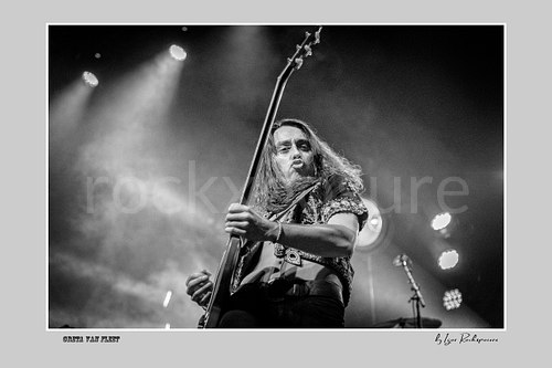 Horizontal black and white image of Greta Van Fleet bassist Sam Kiszka performing live with his bass guitar