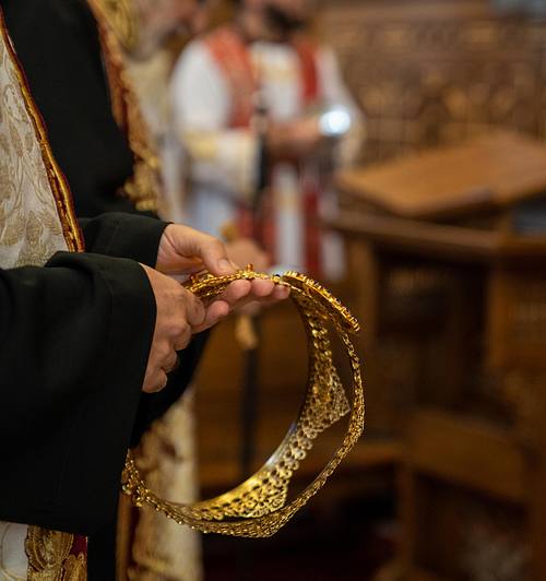 Priest holding crowns for the newlyweds during Ottawa wedding day captured by Kameel Ottawa Photography