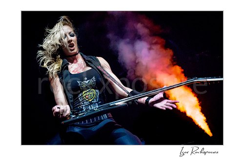 Horizontal color image of Nita Strauss performing live on stage with an electric guitar