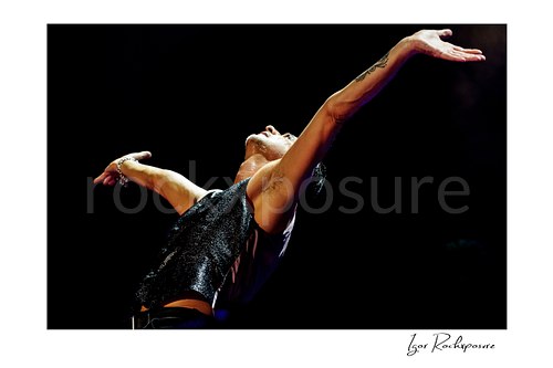Horizontal color image of Depeche Mode singer Dave Gahan with arms raised during a live performance